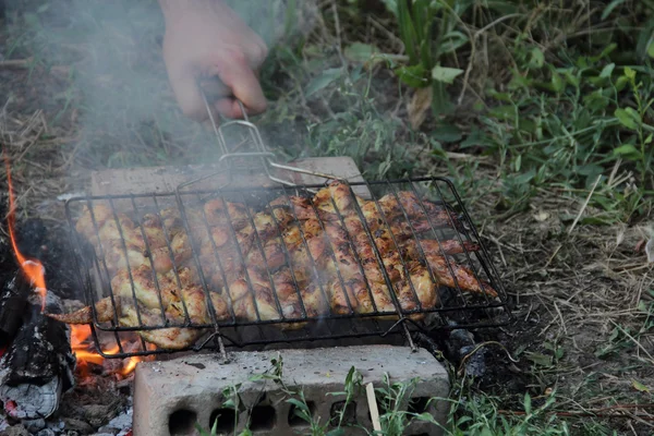 Marinierte Flügel auf einem Gitter für einen Grill über einem Kohlenbecken — Stockfoto