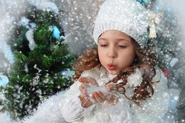 La bella bambina soffia via la neve dalle palme — Foto Stock