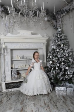 Bir kürk-ağaç hakkında beyaz elbiseli küçük güzel kız