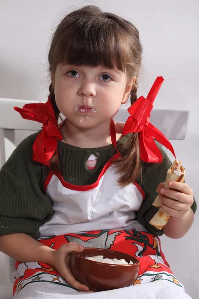 Дівчина їсть млинці зі сметаною — стокове фото
