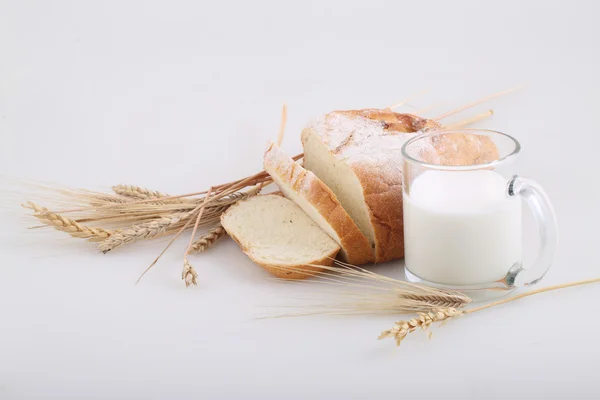 Milk in a transparent mug and a rich roll — Stock Photo, Image