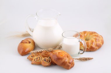 Şeffaf bir sürahi ve beyaz zemin üzerine buns süt 