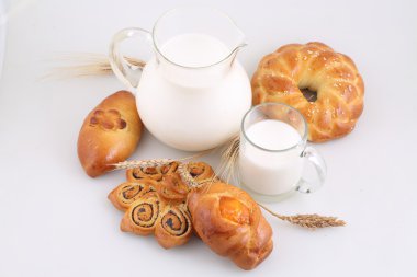 Şeffaf bir sürahi ve beyaz zemin üzerine buns süt 