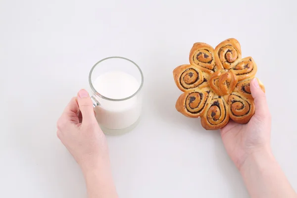 Frauenhände halten ein Brötchen mit Mohn und einen Becher mit Milch — Stockfoto