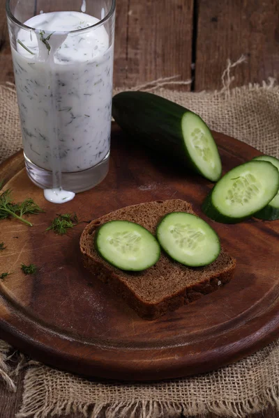 Cocktail de Kefir com um pepino em uma mesa de madeira — Fotografia de Stock