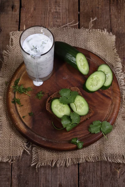 Cocktail de Kefir com um pepino em uma mesa de madeira — Fotografia de Stock