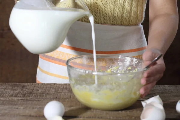 Женщина наливает молоко в тесто — стоковое фото