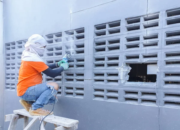 İşçiler havalandırma deliklerini inşa etmek için beton duvarları kesmek için elektrikli değirmen çarkı kullanıyorlar