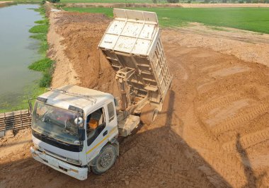 Çöpler yol yapmak için göletin kenarına toprak döker..