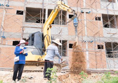 Kazı kazıcı tırmıkları çit direklerinden çukur kazıyor..