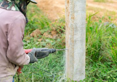 İşçiler fabrikanın etrafına çitler için metal levha döşemek için çimento kazıyorlar.