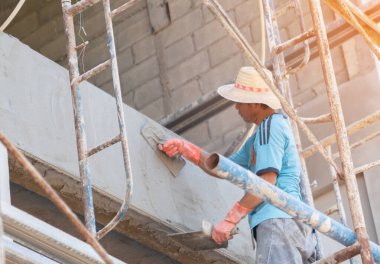 Ev inşaatı için duvara beton yapıştıran işçinin elini kapat..