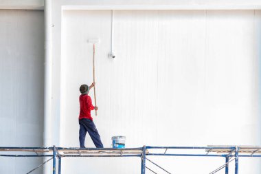İşçiler endüstriyel fabrikalardaki duvarları izole etmek için paten fırçası kullanıyorlar..