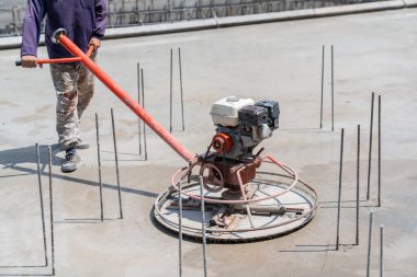 İşçi inşaat alanındaki ıslak betonda güç mala makinesi kullanıyor.