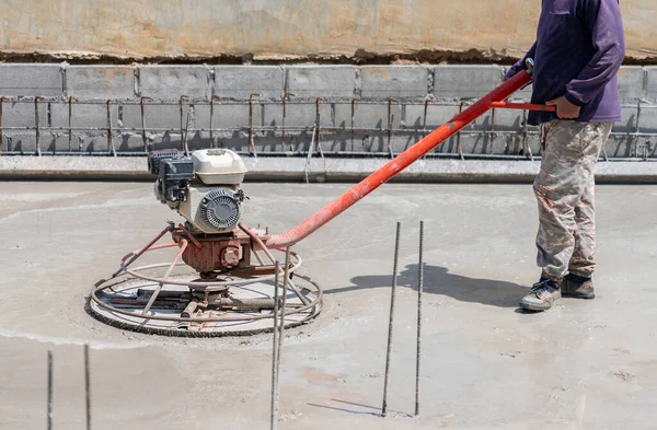 İnşaat alanında beton bitiren elektrikli mala sahip bir işçi