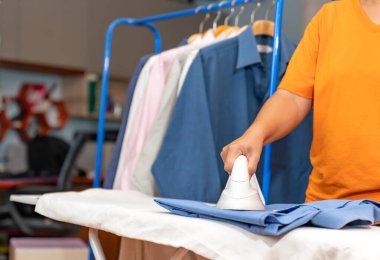 Kadın turuncu gömlekli, ütülü ve askılı parmaklıklı..