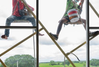 İşçiler camları silmek için binaya tırmanıyorlar. arkaplan ağacı.