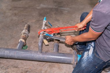 Teknisyen ayarlanabilir anahtarı kullanarak fabrikada sabitlenmek üzere bir vanayı sekme suyundan çıkartıyor.. 