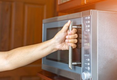 Mutfakta mikrodalga fırını kullanan bir kadın..