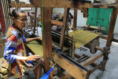 Yogyakarta, Endonezya, 26 Ekim 2015. Eski işçi Lurik Kurnia dokuma fabrikasındaki kumaşı dikkatlice kontrol ediyor..