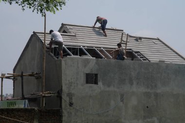 Klaten, Endonezya, 3 Mart 2021. İşçiler evin çatısını yeniliyorlar.