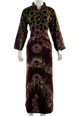 Kravat boyası motifleriyle süslenmiş, yeşil ve morla birleştirilmiş rahat, uzun kadın elbisesi zarafet ve hassasiyeti temsil ediyor. 