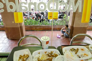 Yogyakarta, Endonezya, 28 Ocak 2013. McDonalds fast food restoranındaki aç bir insanın artıklarını ve öğle yemeğinin tadını çıkaran bir adamın tabağını ve içeceğini.