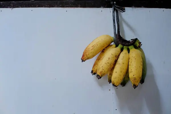Duvarda bir grup sarı muz asılı.