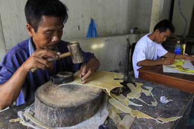 Yogyakarta, Endonezya, 5 Kasım 2015. Wayang kulit ustaları kurutulmuş deriyi oyuyor.. 