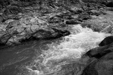 Hızlı akım ve doğal taş dokusuna sahip siyah beyaz bir nehir..