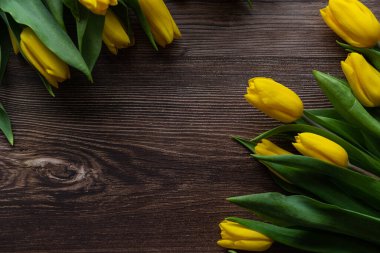 Masanın üzerinde ambalaj kağıdı olan sarı lale demeti.