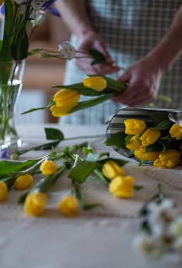 Çiçekçinin elleri lale ve irislerden bir buket çiçek toplar.