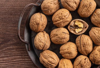 metal bir tepsinin arkasında ceviz var.