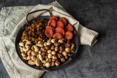 Yuvarlak tepside çeşitli fındık ve kurutulmuş meyveler.