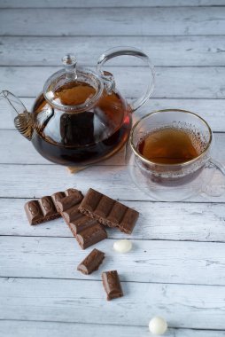 Bir fincan çay ve çaydanlığın arka planında havalanmış sütlü çikolata.