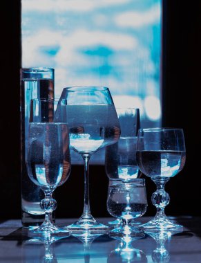 İçecekler için cam şarap bardakları ve arka planda su olan alkol.