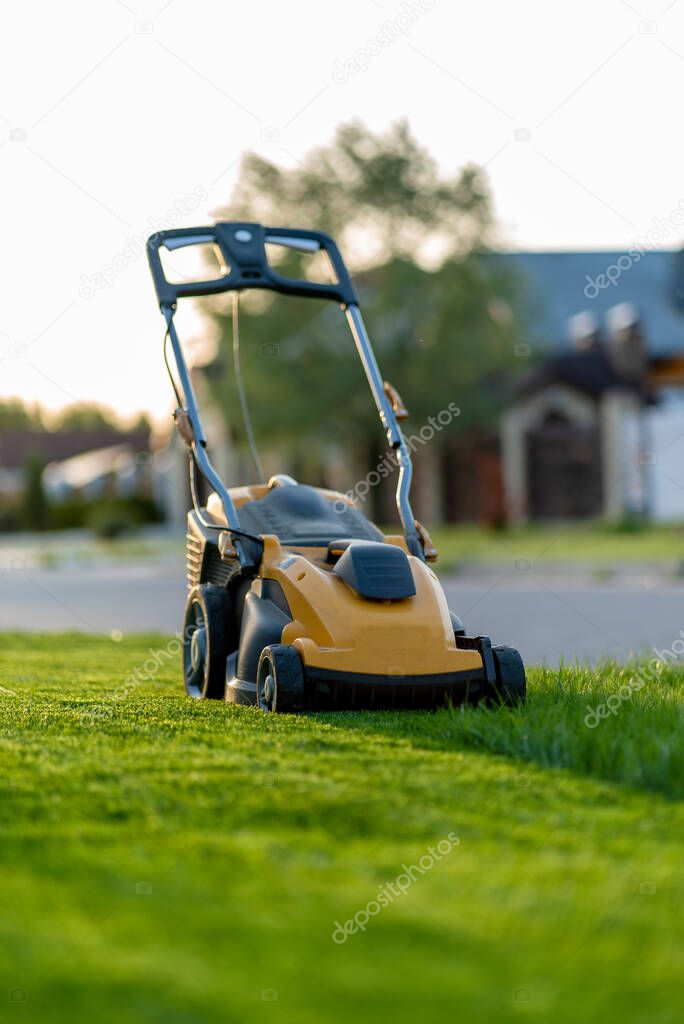 electric lawn mower, man mowing green grass on the lawn