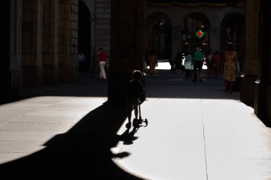 İspanya 'da Santander' de bir plazada scooter süren bir çocuk..