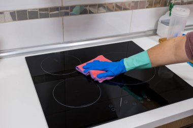 Evdeki masayı temizlemek mutfak masasının yüzeyini dezenfektan sprey şişesiyle sterilize etmek, yüzeyi eldivenlerle yıkamak. COVID-19 içeriden temizleme.