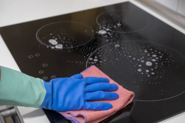 Evdeki masayı temizlemek mutfak masasının yüzeyini dezenfektan sprey şişesiyle sterilize etmek, yüzeyi eldivenlerle yıkamak. COVID-19 içeriden temizleme.