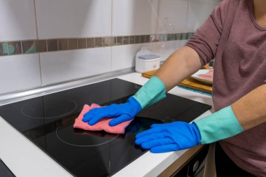 Evdeki masayı temizlemek mutfak masasının yüzeyini dezenfektan sprey şişesiyle sterilize etmek, yüzeyi eldivenlerle yıkamak. COVID-19 içeriden temizleme.