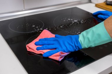 Evdeki masayı temizlemek mutfak masasının yüzeyini dezenfektan sprey şişesiyle sterilize etmek, yüzeyi eldivenlerle yıkamak. COVID-19 içeriden temizleme.