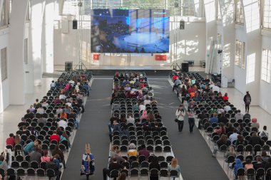 Projeksiyon ekranında akış izleyen ve izleyen ziyaretçiler