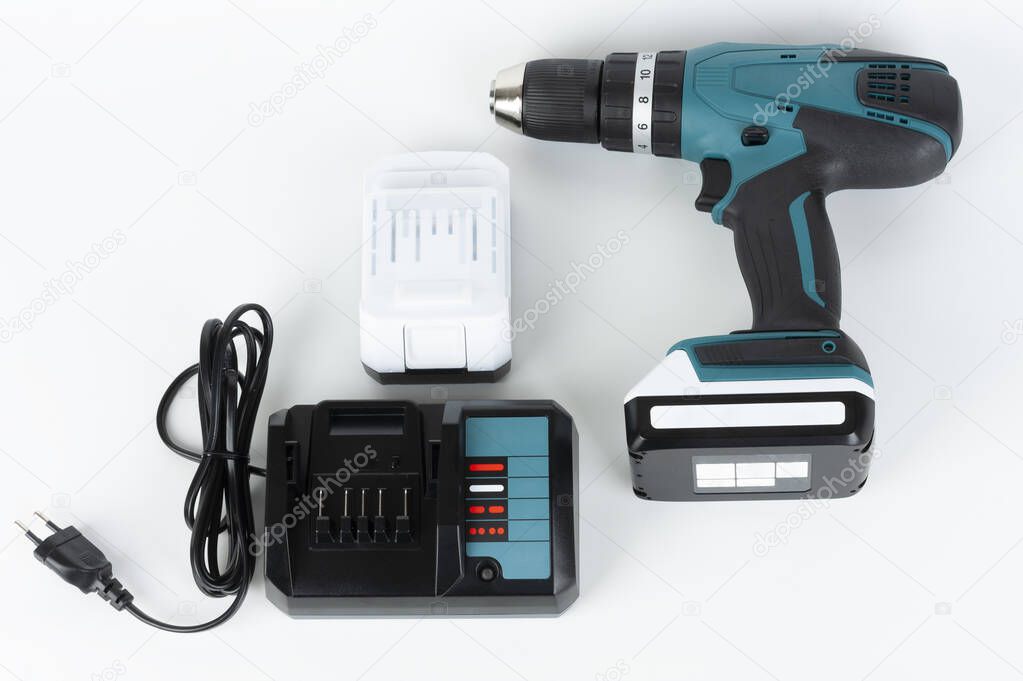 Cordless hammer screwdriver drill, battery charger and second battery on white background. Studio shoot. 