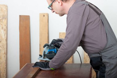 Marangoz ahşap lath elektrikli el aletini kesiyor masa üzerinde, arka plan odaklı iplik testeresi