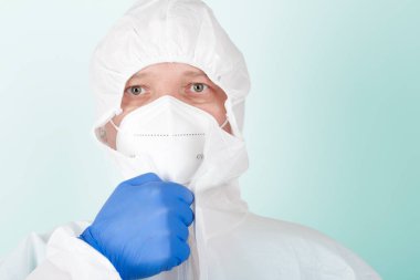 Yüz maskesi olan erkek hemşire koruyucu giysi giyer. Hastanedeki yoğun bakımda virüse karşı korunmak için kişisel koruyucu ekipmanlar..