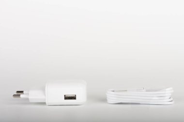 Beyaz şarj aleti ve beyaz kablo beyaz arka planda akıllı telefonu şarj etmek için. 