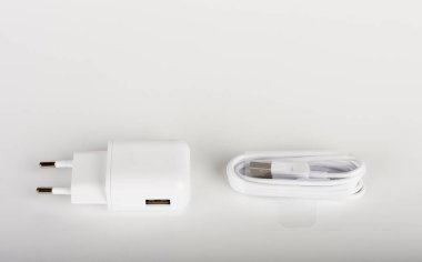 Beyaz şarj aleti ve beyaz kablo beyaz arka planda akıllı telefonu şarj etmek için.