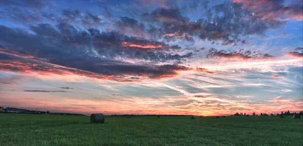 Heuballen auf einer Wiese vor einem schönen Himmel mit Wolken im Sonnenuntergang in hdr Foto — Stockfoto