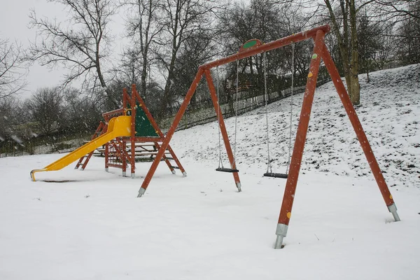 Kleurrijke speeltuin in een park tijdens de sneeuwstorm — Stockfoto